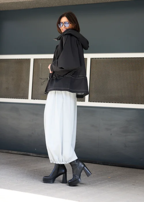 Czarna kurtka oversize z kapturem i kontrastowymi przeszyciami. Lekki model o sportowo-miejskim charakterze z regulacją w talii, idealny do nowoczesnych stylizacji casualowych i streetwearowych.