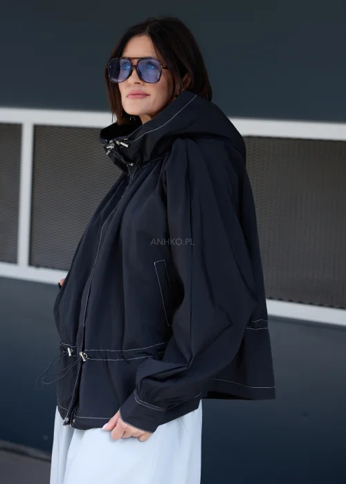 Czarna kurtka oversize z kapturem i kontrastowymi przeszyciami. Lekki model o sportowo-miejskim charakterze z regulacją w talii, idealny do nowoczesnych stylizacji casualowych i streetwearowych.