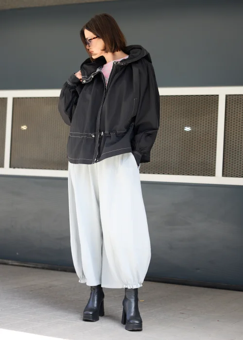 Czarna kurtka oversize z kapturem i kontrastowymi przeszyciami. Lekki model o sportowo-miejskim charakterze z regulacją w talii, idealny do nowoczesnych stylizacji casualowych i streetwearowych.