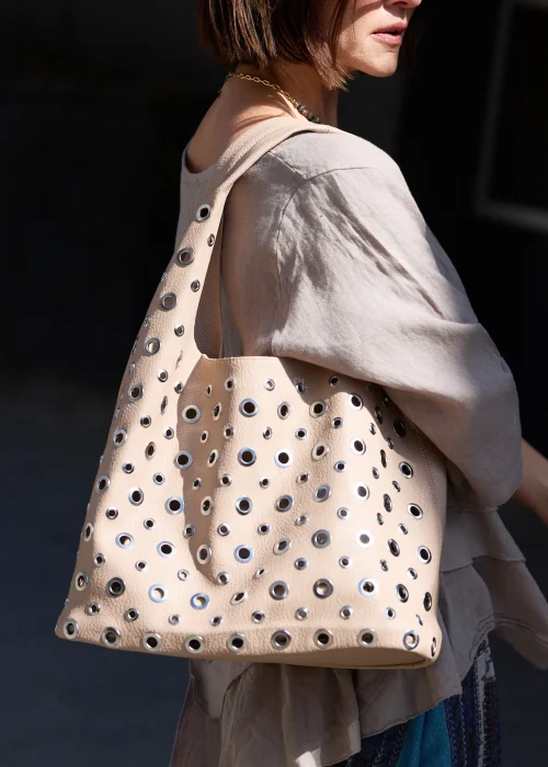 Beżowa torba damska z kosmetyczką  w stylu boho. Miękki model shopper z efektownymi oczkami i szerokim paskiem, idealny do codziennych stylizacji