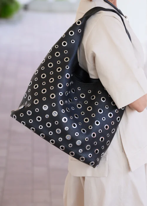 Czarna torba damska z kosmetyczką i ozdobnymi metalowymi oczkami w nowoczesnym stylu urban chic. Miękki model shopper z efektownymi detalami, idealny do codziennych stylizacji.
