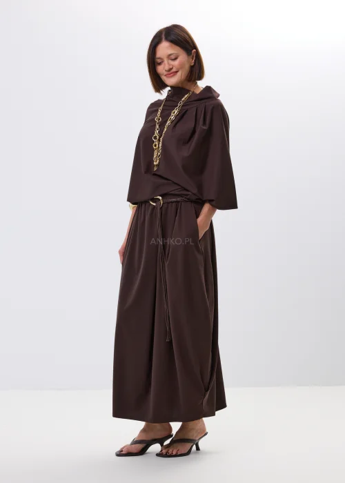 Brązowa spódnica maxi z elastyczną talią i ozdobnym paskiem. Lekko drapowany fason pięknie układa się w ruchu i dodaje stylizacji nowoczesnej elegancji.