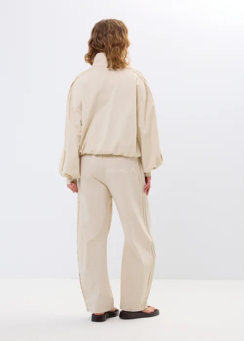 Beżowa bluza oversize na zamek z ozdobnymi wiązaniami i wysokim kołnierzem. Luźny fason nadaje stylizacji nowoczesny i oryginalny charakter.