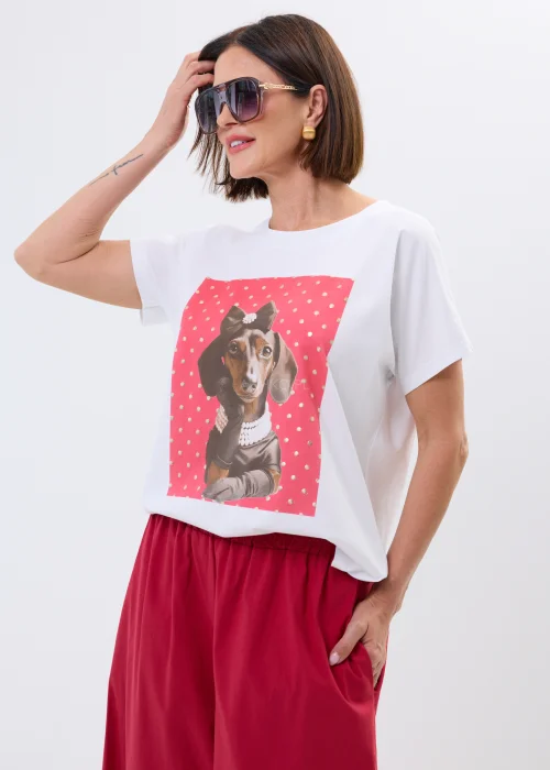 Biały damski t-shirt oversize z nadrukiem jamnika w eleganckiej stylizacji, zestawiony z malinowymi spodniami.