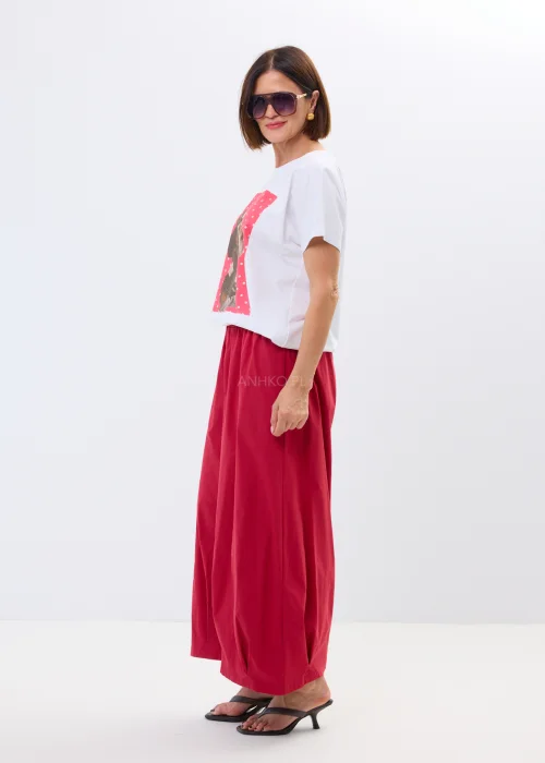 Biały damski t-shirt oversize z nadrukiem jamnika w eleganckiej stylizacji, zestawiony z malinowymi spodniami.