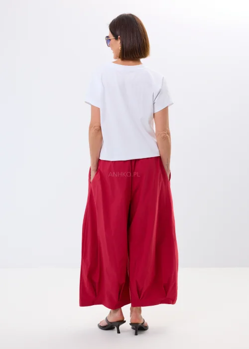 Biały damski t-shirt oversize z nadrukiem jamnika w eleganckiej stylizacji, zestawiony z malinowymi spodniami.