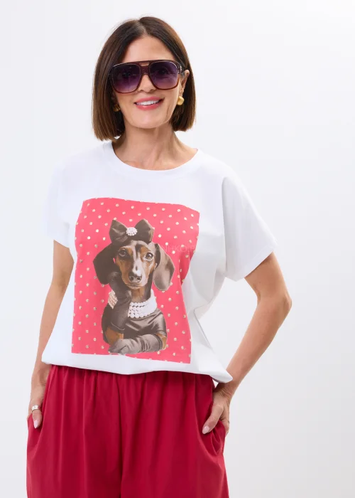 Biały damski t-shirt oversize z nadrukiem jamnika w eleganckiej stylizacji, zestawiony z malinowymi spodniami.