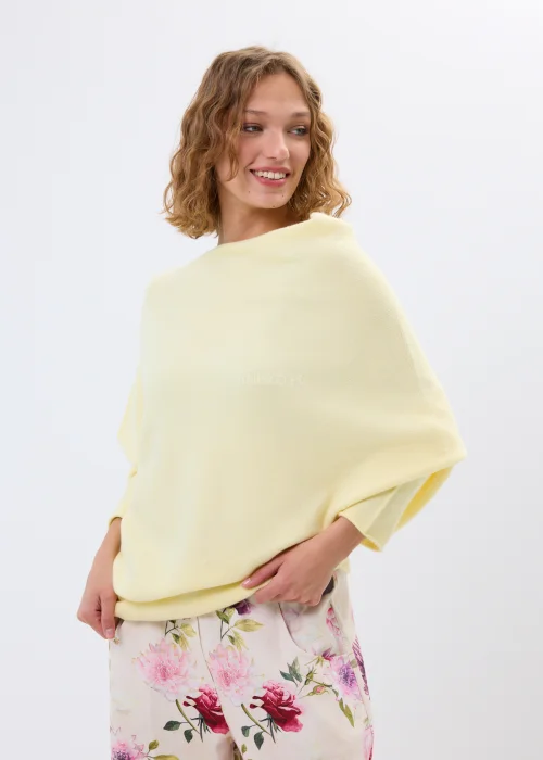 Masełkowy sweter damski oversize z miękkiej dzianiny i szerokim dekoltem typu boat neck. Lekki sweter w pastelowym odcieniu zestawiony z kwiatowymi spodniami w kobiecej casualowej stylizacji.