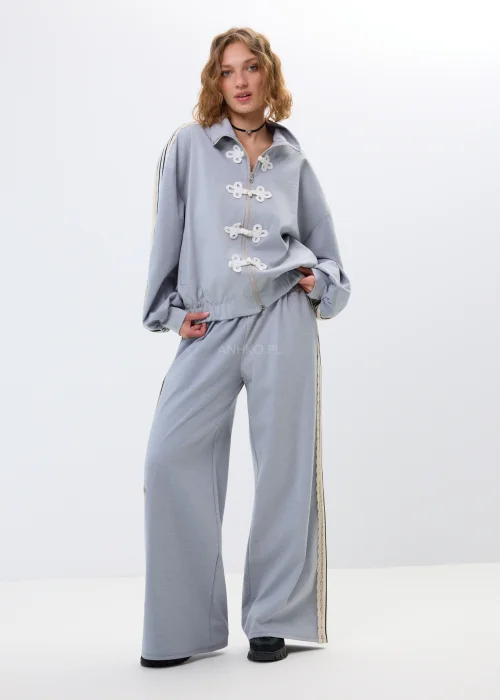 Damska bluza rozpinana w jasnoszarym kolorze z ozdobnymi wiązaniami i stójką. Oversize’owy fason z szerokimi rękawami tworzy wygodny, nowoczesny look.