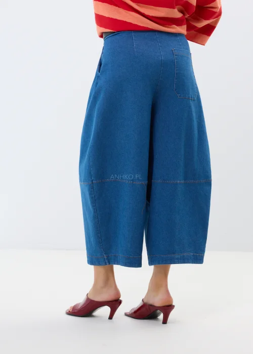 Granatowe jeansy damskie culotte z szerokimi nogawkami i wysokim stanem. Luźny fason w miejskiej stylizacji z bordowymi klapkami.