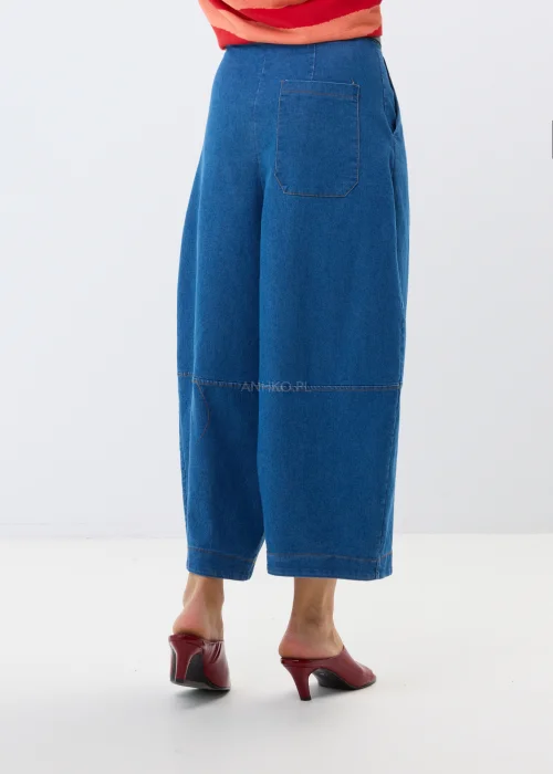 Granatowe jeansy damskie culotte z szerokimi nogawkami i wysokim stanem. Luźny fason w miejskiej stylizacji z bordowymi klapkami.