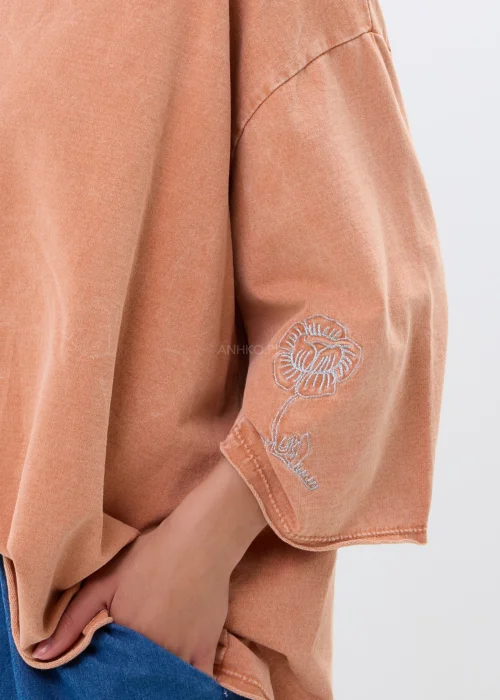 Oversize’owa bluzka w morelowym odcieniu z szerokimi rękawami i haftowanym kwiatem. Swobodny fason zapewnia wygodę i casualowy styl.