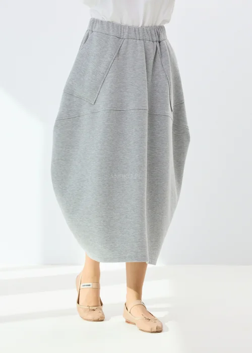 Szara spódnica midi o bombkowym kroju z elastyczną talią i dużymi kieszeniami. Model z miękkiej dzianiny wyróżnia się nowoczesnym, oversize’owym fasonem.