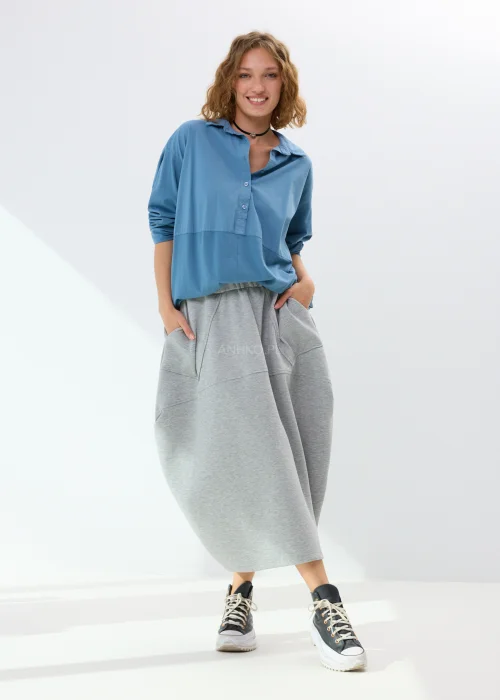 Niebieska koszula damska oversize z kołnierzem i guzikami z przodu, wykonana z bawełny z dodatkiem elastanu. Model zestawiony ze wzorzystą spódnicą w stylizacji miejskiej.