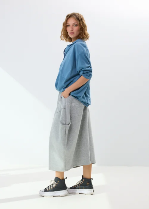 Niebieska koszula damska oversize z kołnierzem i guzikami z przodu, wykonana z bawełny z dodatkiem elastanu. Model zestawiony ze wzorzystą spódnicą w stylizacji miejskiej.