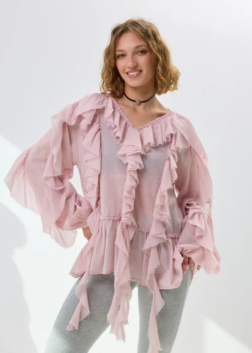 Pudroworóżowa bluzka damska z falbanami i luźnym fasonem boho. Zwiewny model z szerokimi rękawami i romantycznym wykończeniem przyciąga uwagę efektownymi detalami.