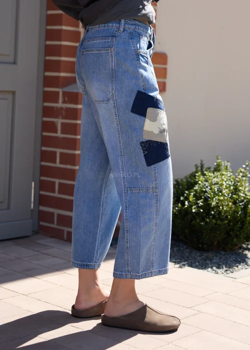 Jeansowe spodnie wide leg z naszywkami moro i luźnym fasonem w miejskiej casualowej stylizacji.