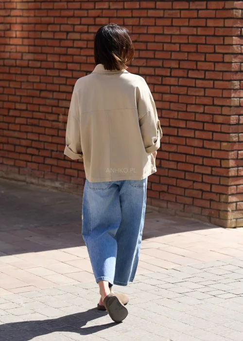 Damska beżowa bluzka oversize z kołnierzykiem i dużymi kieszeniami w casualowej stylizacji z jeansami.