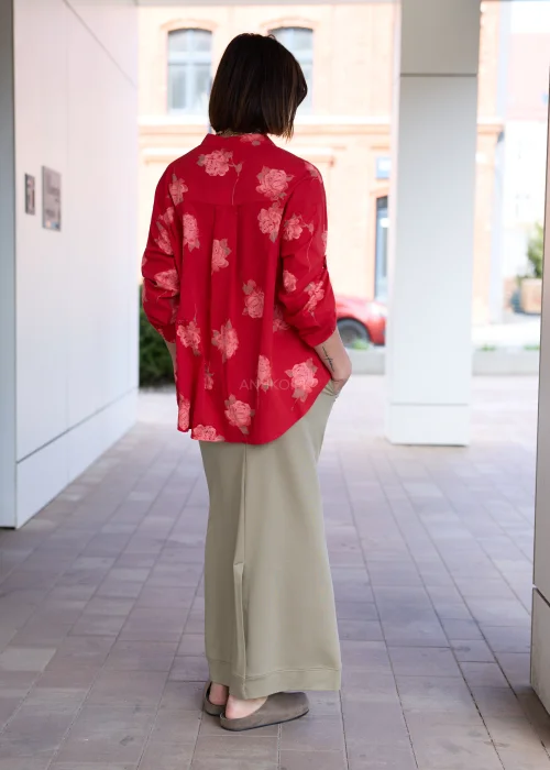 Damska czerwona koszula oversize z różanym printem, kieszenią na piersi i podwijanymi rękawami. Elegancka stylizacja z oliwkową spódnicą podkreśla kobiecy, nowoczesny charakter outfitu.