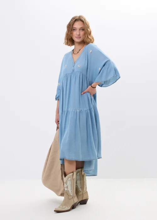 Jasnoniebieska sukienka jeansowa oversize z falbanami i dekoltem V. Zwiewny model z ozdobnymi detalami idealny do boho i casualowych stylizacji.