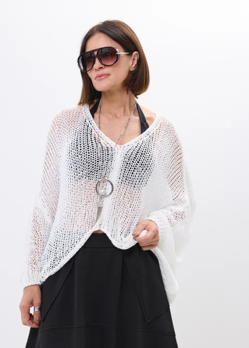 Biały ażurowy sweter oversize o luźnym splocie z dekoltem V. Lekki model idealny do letnich stylizacji i narzutek na top lub kostium kąpielowy.
