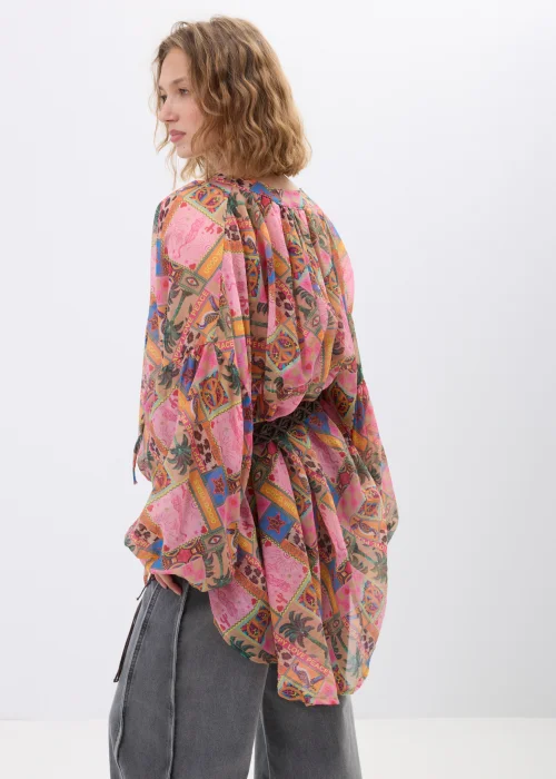 Bluzka damska oversize w stylu boho z multikolorowym printem patchworkowym w odcieniach różu, pomarańczu i brązu. Zwiewny model z szerokimi rękawami oraz wiązaniem w talii świetnie uzupełnia casualowe i artystyczne stylizacje.