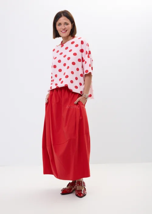 Różowa bluzka oversize w czerwone grochy z szerokim rękawem i minimalistycznym dekoltem. Kobiecy model idealny do  stylizacji w klimacie retro chic i casual fashion.