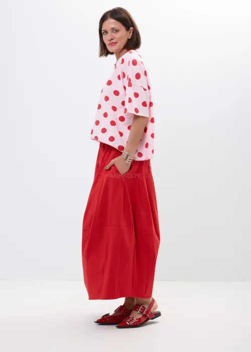 Różowa bluzka oversize w czerwone grochy z szerokim rękawem i minimalistycznym dekoltem. Kobiecy model idealny do  stylizacji w klimacie retro chic i casual fashion.