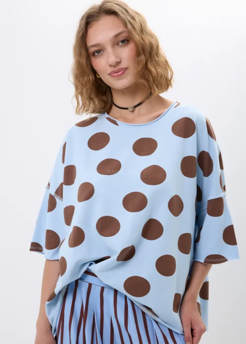 Bluzka oversize w błękitnym kolorze z brązowym wzorem w grochy. Luźny fason i szerokie rękawy zapewniają wygodę oraz modny, swobodny wygląd.