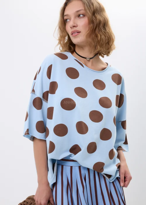 Bluzka oversize w błękitnym kolorze z brązowym wzorem w grochy. Luźny fason i szerokie rękawy zapewniają wygodę oraz modny, swobodny wygląd.