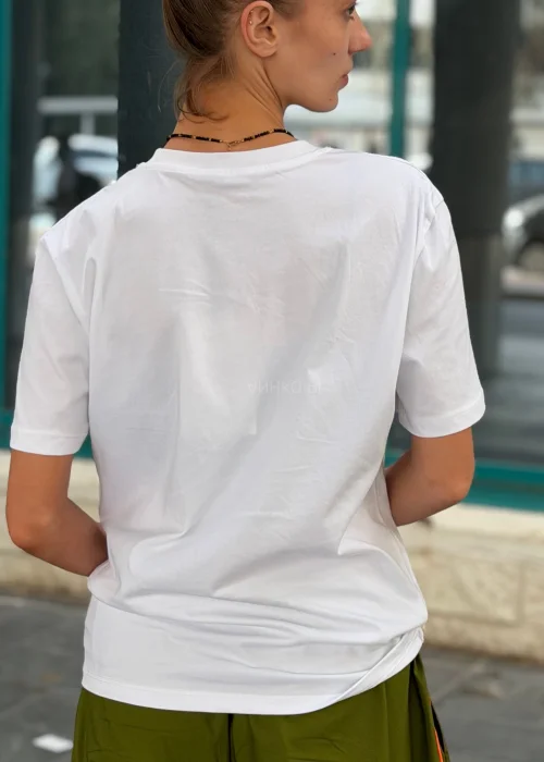 Biały T-shirt damski z nadrukiem „I Have Nothing To Wear” w czarnym kolorze. Luźny model casual zestawiony z zielonymi spodniami i okularami przeciwsłonecznymi.
