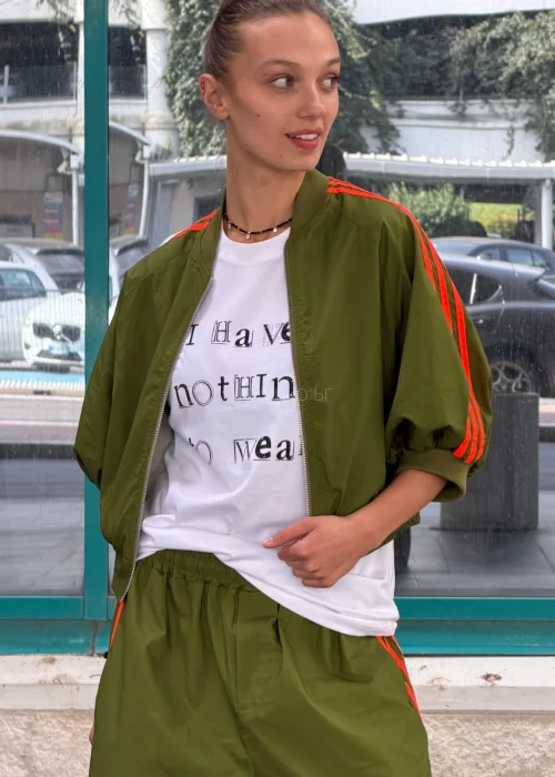 Biały T-shirt damski z nadrukiem „I Have Nothing To Wear” w czarnym kolorze. Luźny model casual zestawiony z zielonymi spodniami i okularami przeciwsłonecznymi.