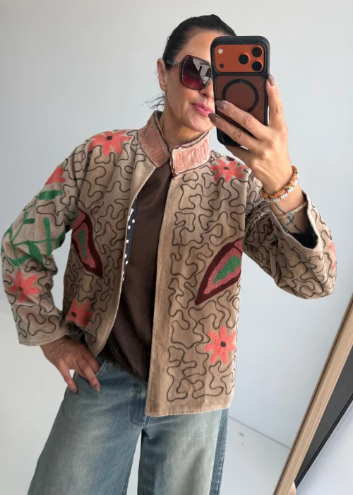 Żakiet damski w kolorze kremowego beżu z dekoracyjnym haftem kwiatowym oraz motywem motyla w odcieniach różu, zieleni i bordo. Artystyczny model w stylu boho z oryginalnym wzorem.