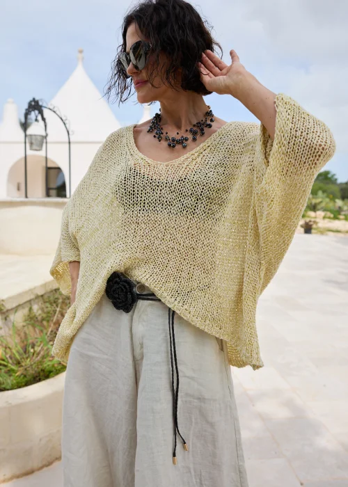 Żółty sweter damski o luźnym oversize'owym kroju z ażurowym splotem i szerokimi rękawami. Lekka dzianina nadaje stylizacji swobodny charakter i doskonale komponuje się z lnianymi spodniami.