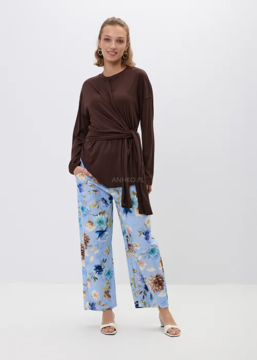 Brązowa bluzka z efektownym wiązaniem w talii i luźnym fasonem oversize. Model z długim rękawem oraz asymetrycznym drapowaniem podkreśla sylwetkę i tworzy elegancką, kobiecą stylizację.