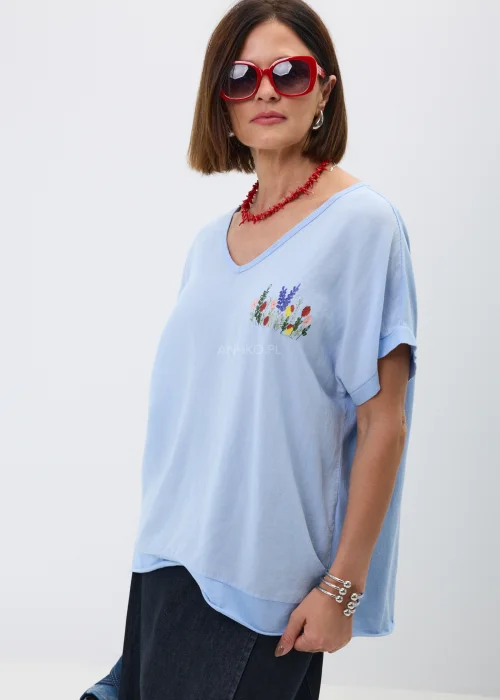 Bluzka w kolorze baby blue z dekoltem V i subtelnym haftem kwiatowym na piersi. Luźny fason oversize z krótkim rękawem nadaje stylizacji lekkości i doskonale komponuje się z jeansowymi oraz casualowymi zestawami.
