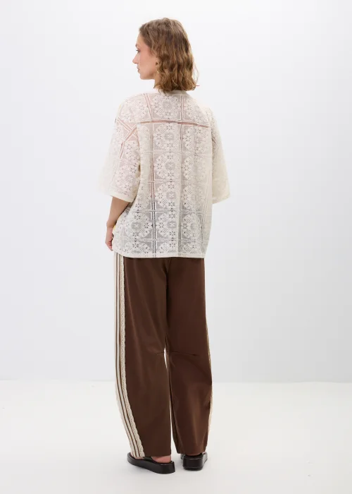 Bluzka oversize w paski w odcieniach beżu, brązu i żółci z ozdobną koronkową wstawką oraz koronkowym tyłem. Luźny fason z krótkim rękawem łączy casualowy charakter z romantycznymi detalami.