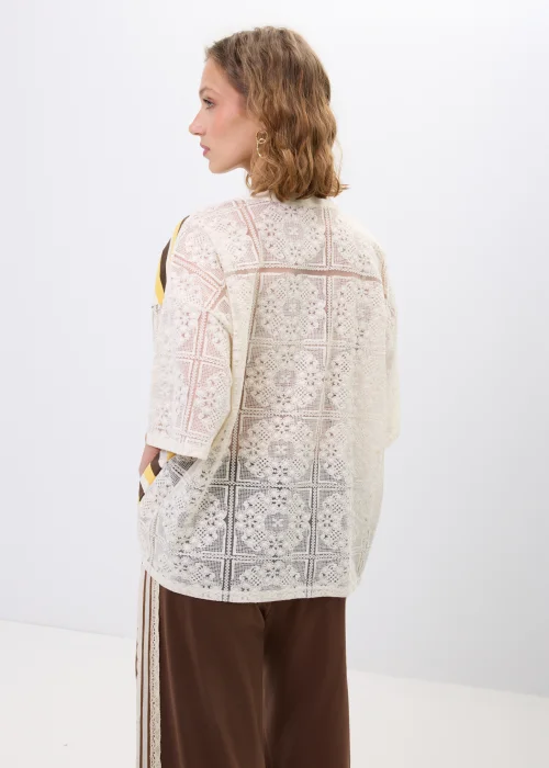 Bluzka oversize w paski w odcieniach beżu, brązu i żółci z ozdobną koronkową wstawką oraz koronkowym tyłem. Luźny fason z krótkim rękawem łączy casualowy charakter z romantycznymi detalami.