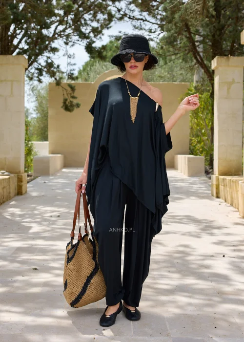Czarna oversize’owa bluzka o asymetrycznym fasonie z efektownym dekoltem opadającym na jedno ramię. Zwiewny materiał i luźny krój tworzą elegancką, nowoczesną stylizację.