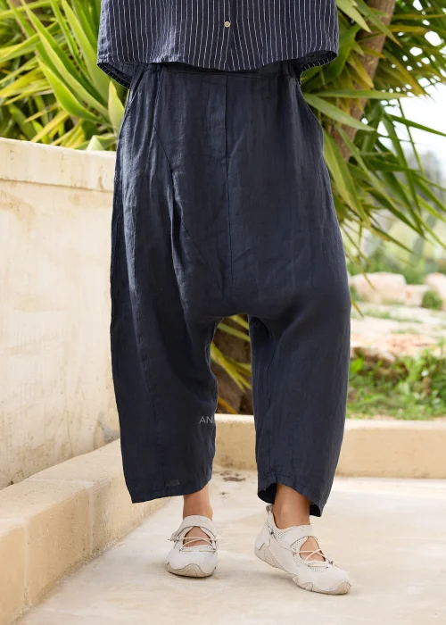 Granatowe lniane spodnie damskie o luźnym kroju z obniżonym krokiem i szerokimi nogawkami. Komfortowy model w stylu casual zestawiony z lnianą koszulą w paski.