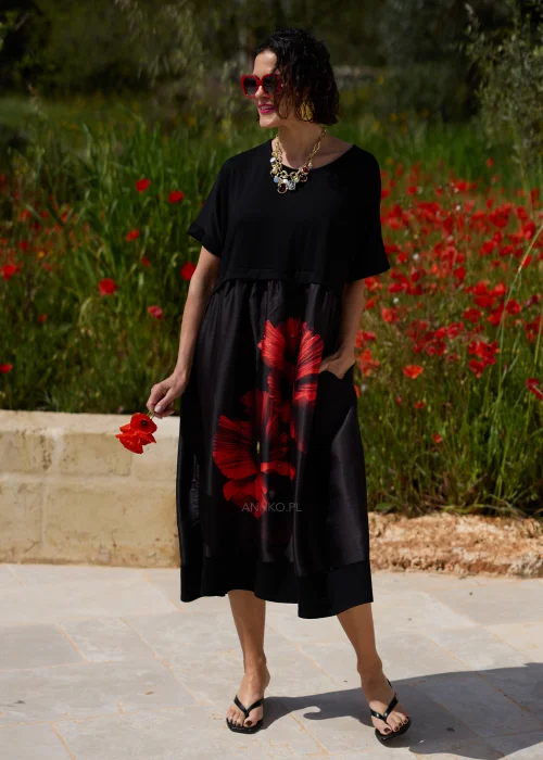 Czarna sukienka midi z efektownym czerwonym motywem maków, luźnym fasonem i praktycznymi kieszeniami. Elegancki model z krótkim rękawem idealny do codziennych i wyjątkowych stylizacji w kobiecym, artystycznym stylu.