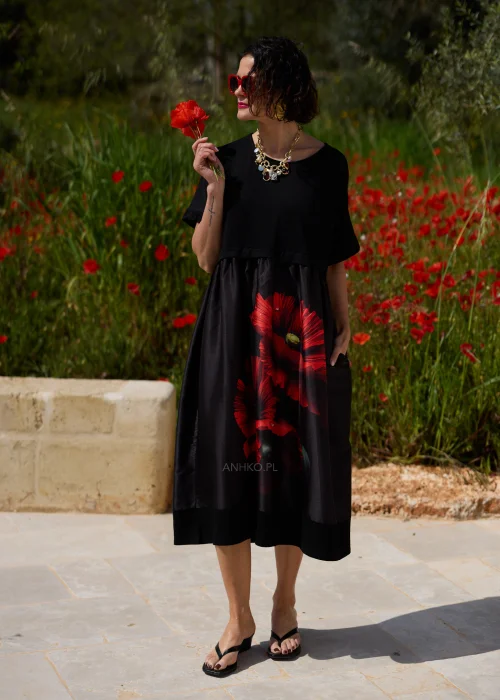 Czarna sukienka midi z efektownym czerwonym motywem maków, luźnym fasonem i praktycznymi kieszeniami. Elegancki model z krótkim rękawem idealny do codziennych i wyjątkowych stylizacji w kobiecym, artystycznym stylu.