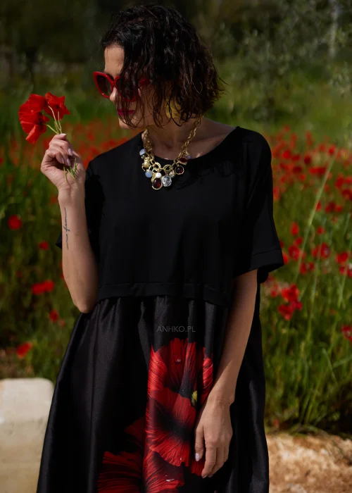 Czarna sukienka midi z efektownym czerwonym motywem maków, luźnym fasonem i praktycznymi kieszeniami. Elegancki model z krótkim rękawem idealny do codziennych i wyjątkowych stylizacji w kobiecym, artystycznym stylu.