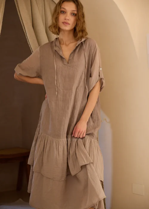 Lniana sukienka maxi z kapturem w odcieniu taupe, z dekoracyjną falbaną u dołu i podwijanymi rękawami. Swobodny fason w stylu boho doskonale sprawdzi się w naturalnych, codziennych i eleganckich stylizacjach.