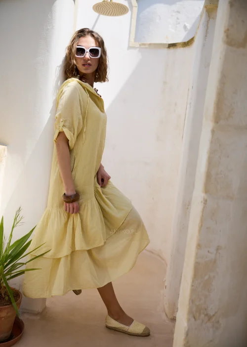 Jasnożółta sukienka midi z kapturem, falbaną u dołu i podpinanymi rękawami 3/4. Luźny model w stylu boho, idealny na wakacyjne spacery i codzienne letnie stylizacje.