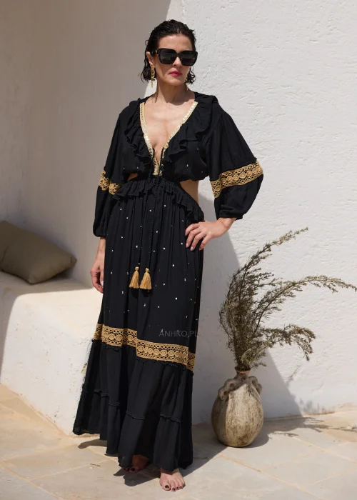 Czarna sukienka maxi w stylu boho z ażurowymi zdobieniami w kolorze złota, głębokim dekoltem V i wycięciami w talii. Zwiewny model z szerokimi rękawami i ozdobnym wiązaniem z chwostami, idealny na wakacyjne i wieczorowe stylizacje.