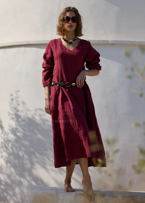 Bordowa lniana sukienka midi z dekoltem V i długimi rękawami o luźnym, naturalnym fasonie. Minimalistyczny krój podkreśla elegancję stylizacji w klimacie boho i slow fashion.