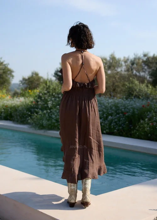 Lniana sukienka maxi w odcieniu brązu z asymetryczną falbaną przy dekolcie i dole oraz cienkimi ramiączkami. Zwiewny model w stylu boho, idealny na wakacyjne stylizacje i codzienne letnie wyjścia.