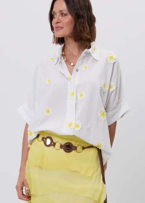 Biała koszula damska z dekoracyjnymi aplikacjami w kształcie stokrotek, krótkim podwiniętym rękawem i klasycznym kołnierzykiem. Luźny model w stylu boho, idealny do letnich stylizacji ze spódnicami i lekkimi spodniami.