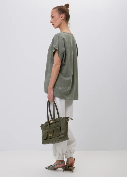 Oliwkowy damski T-shirt oversize z białym kwiatowym nadrukiem i podwijanymi rękawami. Luźna bluzka w naturalnym stylu, zestawiona z białymi szerokimi spodniami i torebką, idealna do codziennych stylizacji.
